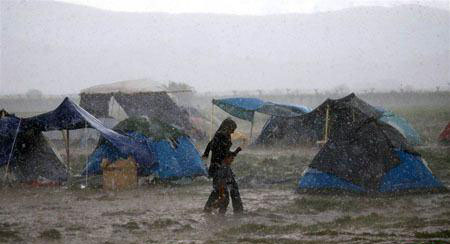 فرار مادر و کودک پناهجو از باران سیل‌آسا +عکس