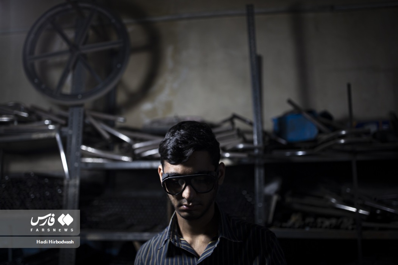 یکی از کارگران کارگاه ویلچر سازی برای پیشگیری از آسیب دیدگی چشمانش از عینک مخصوص استفاده کرده است
