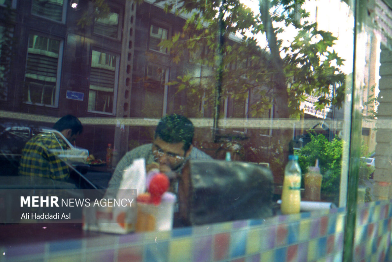 مردی در یک اغذیه فروشی در خیابان قرنی در حال غذا خوردن است