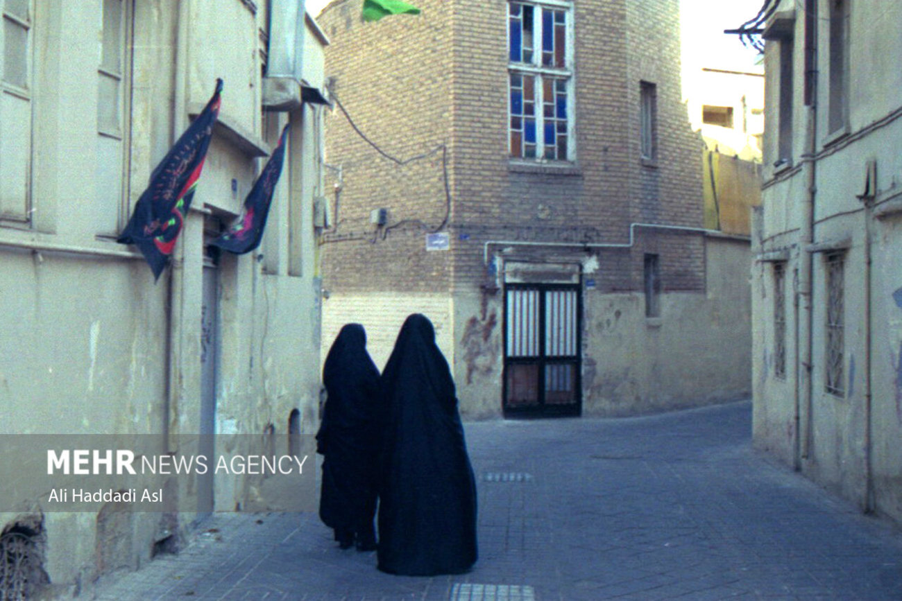 دو خانم در محله امام زاده یحیی(ع) در حال گذر از یک کوچه هستند