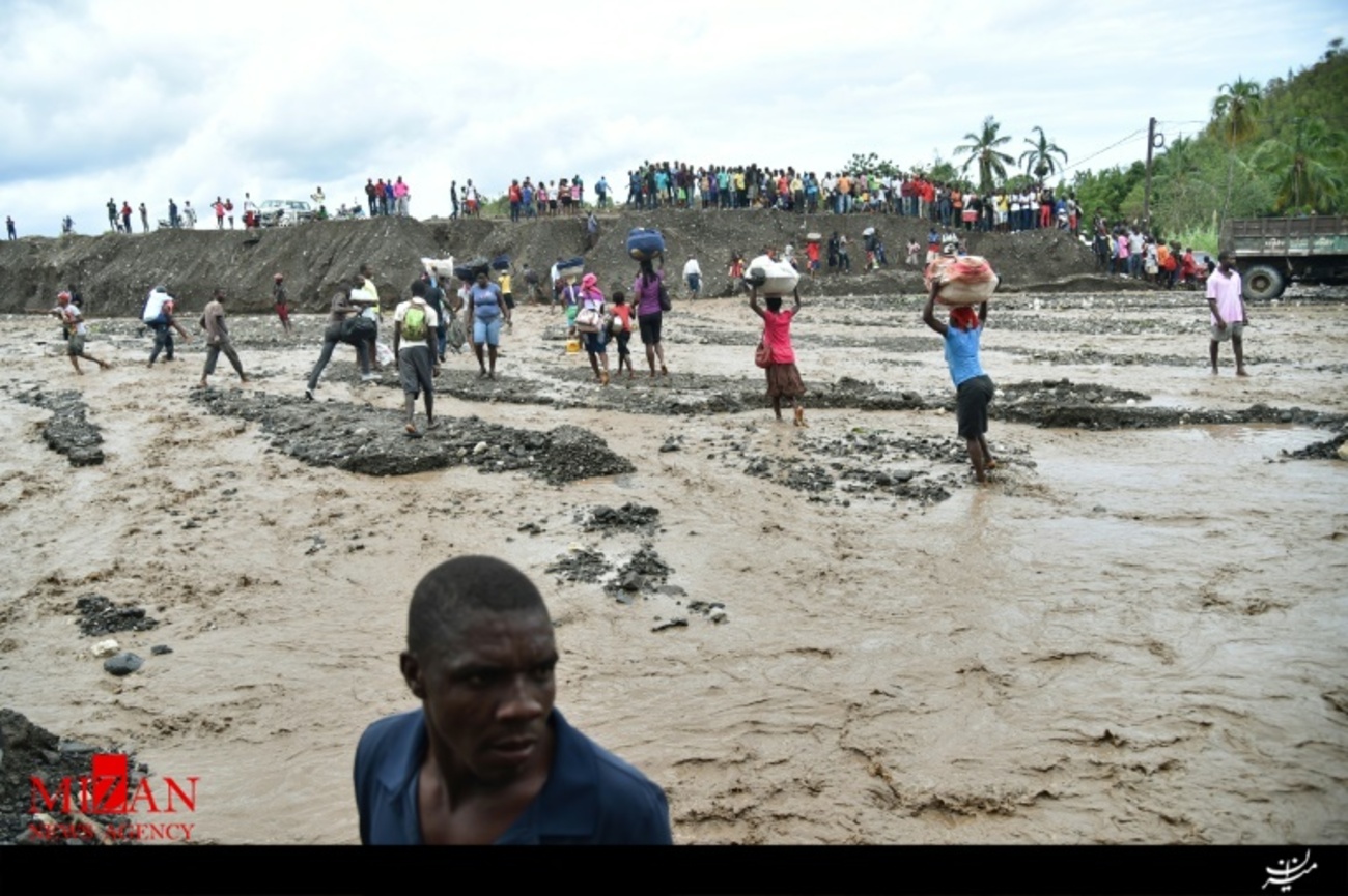 مردم طوفان زده هائیتی در حال عبور از رودخانه La Digue در جنوب غربی پورتو پرنس