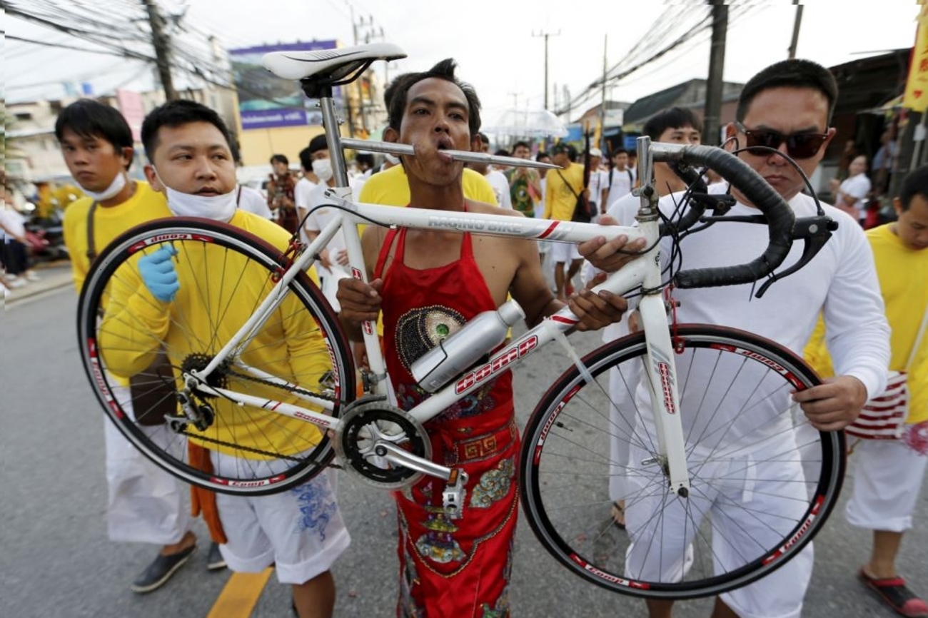یکی از شیفتگان از Samkong حرم چینی  با یک دوچرخه در دهان خود  در طول صفوف جشنواره های گیاهی سالانه در پوکت/ خورخه سیلوا/رویترز