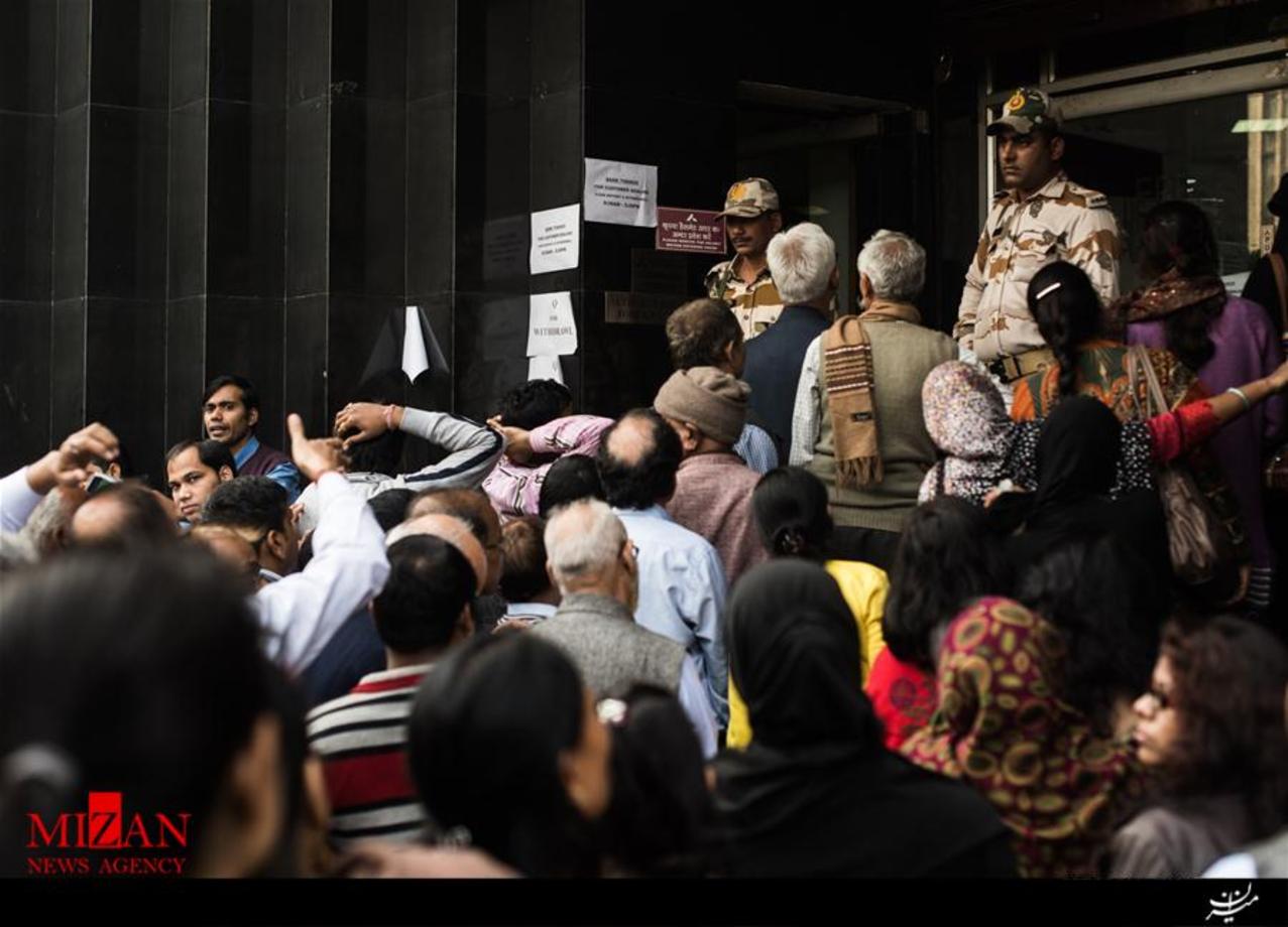 نیروهای امنیتی در حال ایجاد نظم ئر میان صف در انتظار مردم برای برداشت پول نقد در ورودی یک بانک در مرکز شهر دهلی نو هند