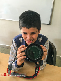 یک دانش آموز روشن دل در زمان استراحت دوربین عکاسی را لمس می کند. 