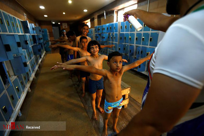 ضدعفونی کردن کودکان عراقی در استخر قبل از وارد شدن به آب.