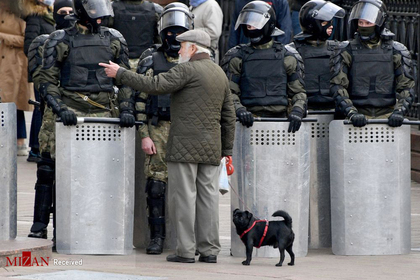مردی با سگش در مقابل پلیس ضد شورش در مینسک