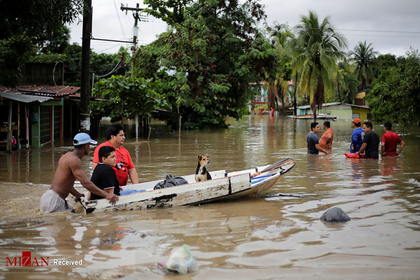 مردم در حال هل دادن قایقی با سگی درون آن پس از سیل در هندوراس
