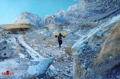 معدنچی در حال حمل سنگ گوگرد از کوه آتشفشانی کاوا ایجن در اندونزی . دستمزد معدنچیان حدود 8-7 دلار در روز است.
