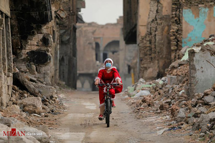زن عراقی در حال دوچرخه سواری با لباس بابانوئل.
